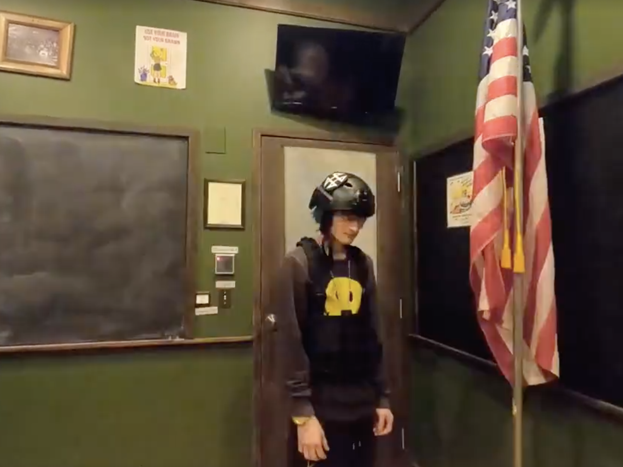 caption: Crimo made rap music under the name Awake The Rapper. In one video, he wears a helmet and vest inside an empty classroom and scatters bullets across the floor.