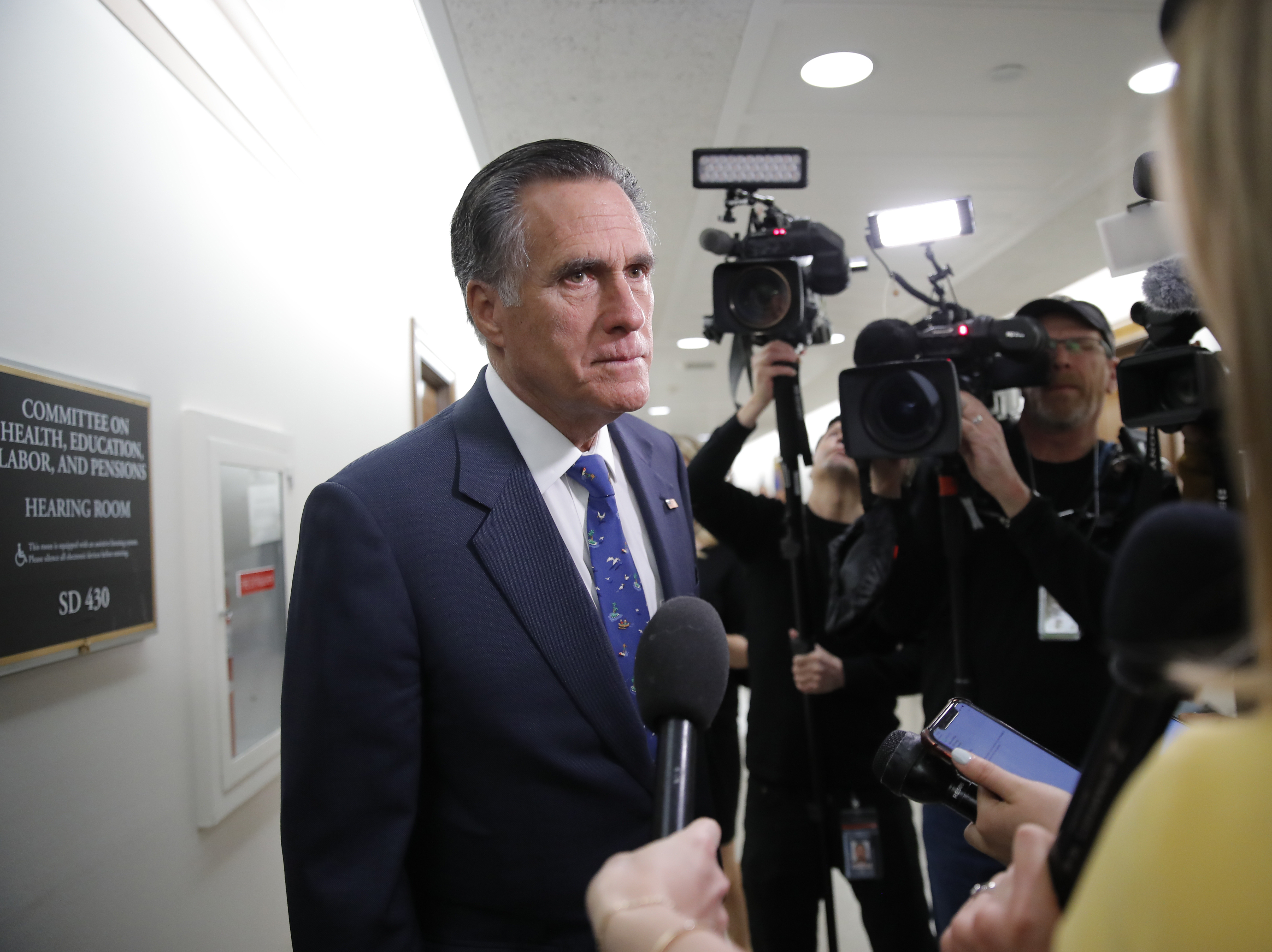 caption: Sen. Mitt Romney, R-Utah, pauses to speak to media on Capitol Hill on Thursday. Romney is among the officials who criticized the flouting of airport guidelines for greeting returning missionaries.