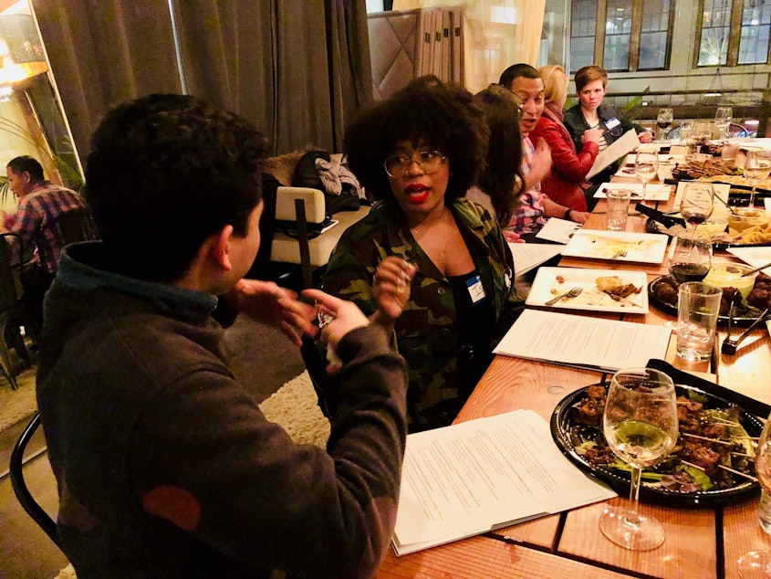caption: Ishea Brown talks with Joe Santiago at KUOW's first Pop-Up Curiosity Club dinner at The Cloud Room in Seattle. February 28, 2019. 