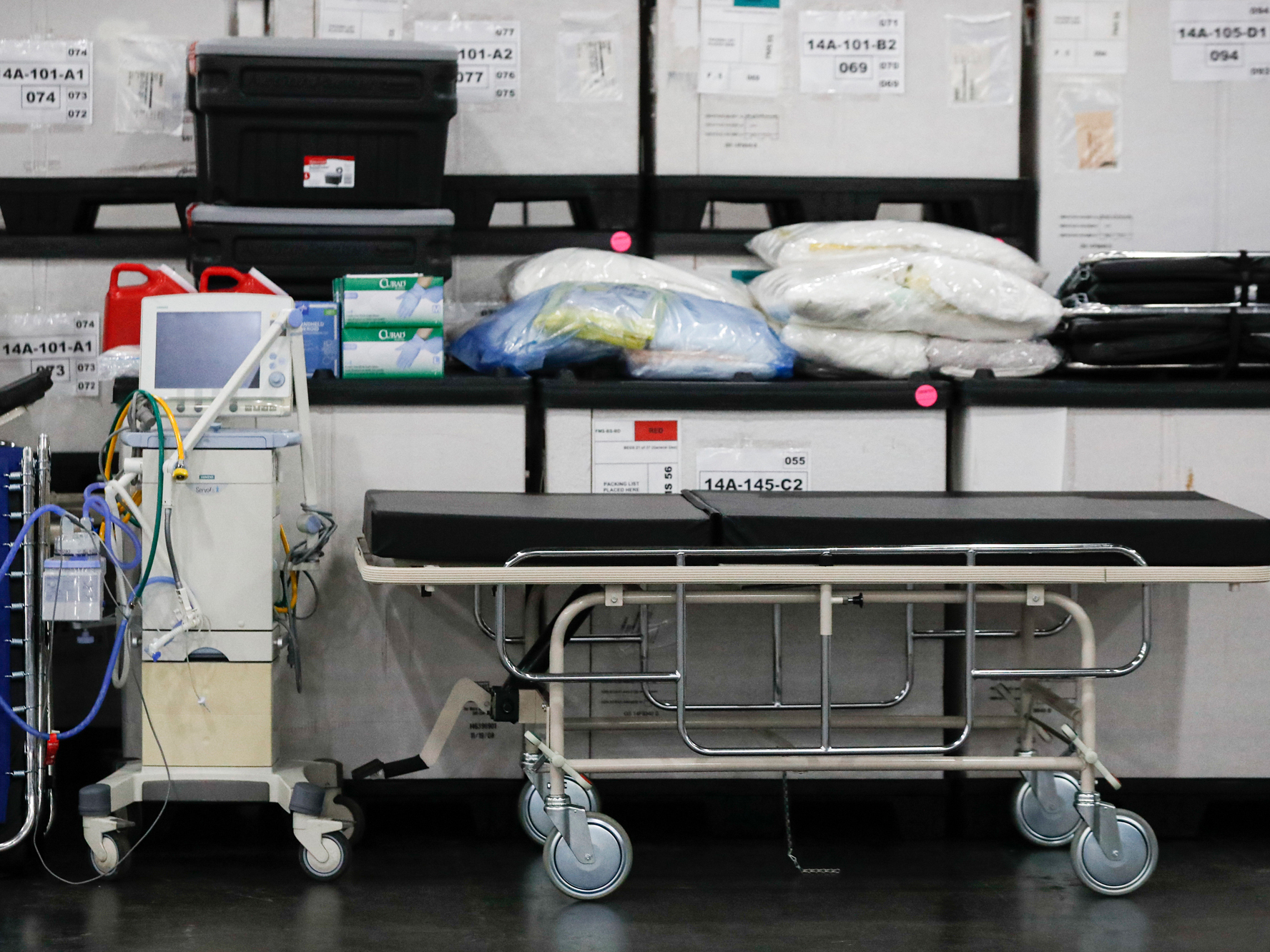 caption: A ventilator alongside medical supplies and a stretcher is displayed before a news conference at the Javits Center in New York City on March 23.