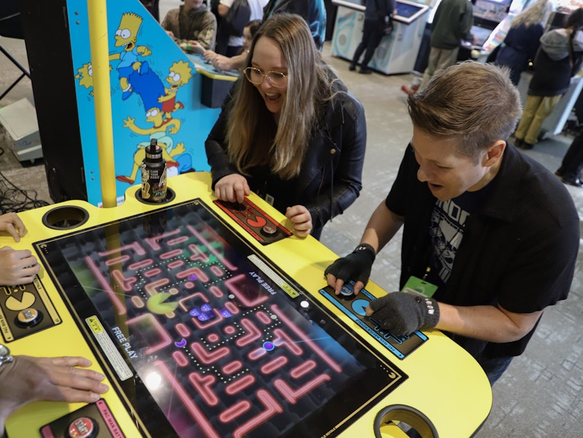 caption: KUOW's Katie Campbell and Dyer Oxley take a break from Emerald City Comic Con in the arcade room on Feb. 29, 2024.