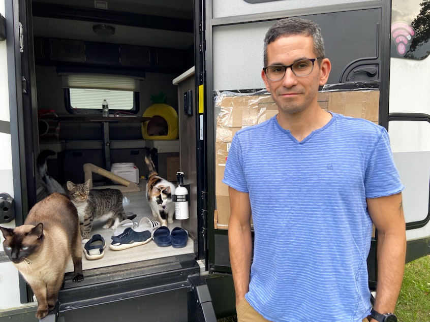 caption: Mike Johansen stands by the door of the camping trailer where the couple is living while they wait for construction on their new home to be finished.