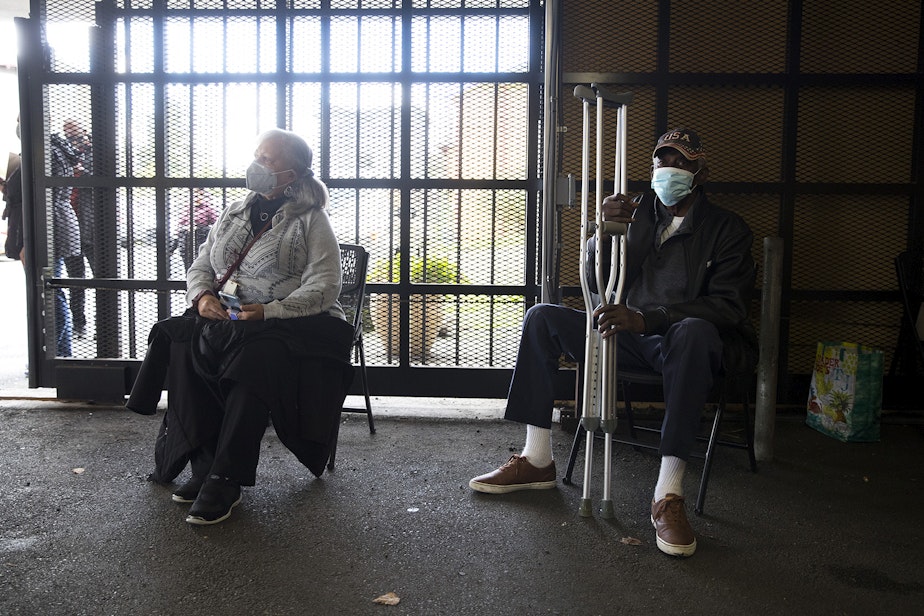 caption: Patricia Riales, left, and Ulysses Glenn, right, wait for 15 minutes after receiving the first dose of the Moderna Covid-19 vaccine on Wednesday, February 3, 2021, during a vaccine clinic set up by the Somali Health Board in partnership with the Othello Station Pharmacy to vaccinate 100 seniors in the community at the Brighton Apartments complex on Rainier Avenue South in Seattle. 