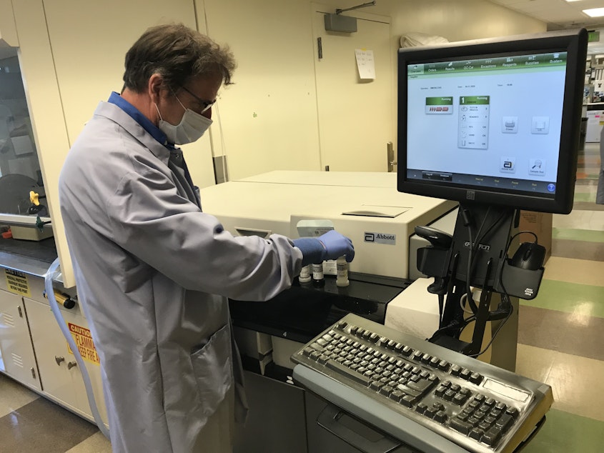 caption: UW Virology Lab Manager Greg Pepper works with a Covid-19 antibody test manufactured by the Illinois-based health care company, Abbott Laboratories, Inc. 