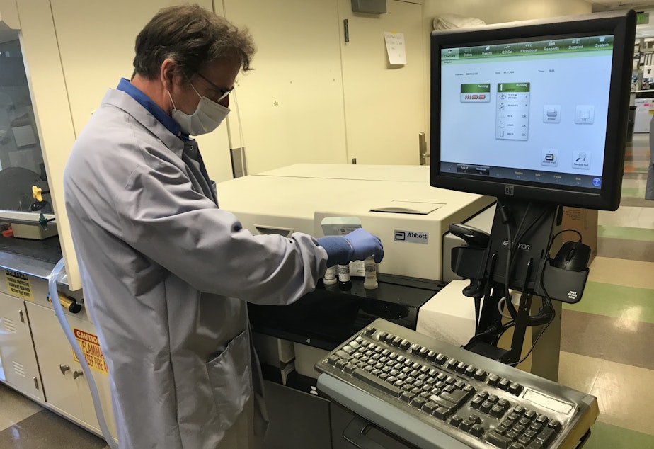 caption: UW Virology Lab Manager Greg Pepper works with a Covid-19 antibody test manufactured by the Illinois-based health care company, Abbott Laboratories, Inc. 