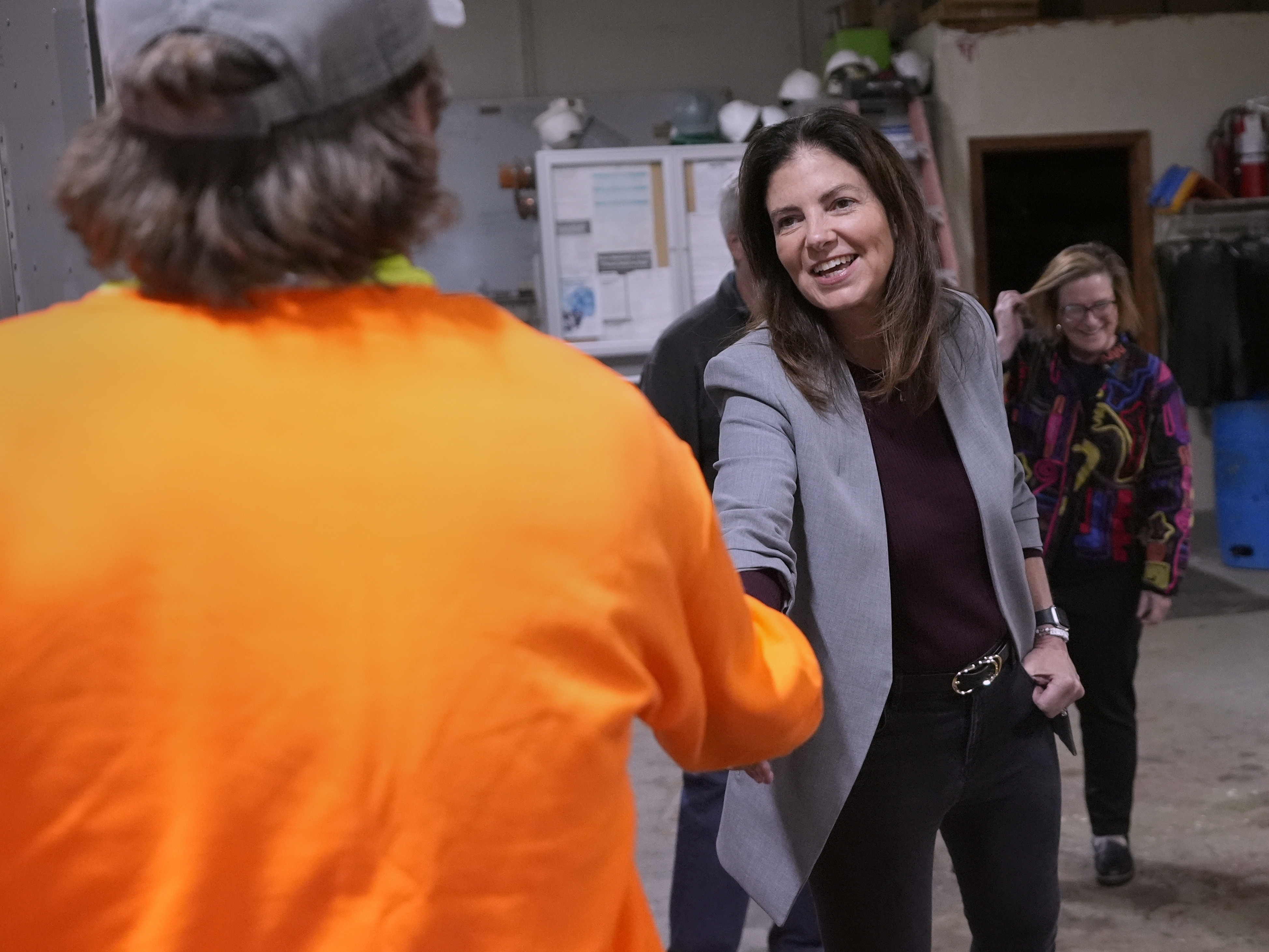 caption: Republican Kelly Ayotte shakes hands with an employee during a visit to a local concrete coating business on Oct. 16 in Manchester, N.H.