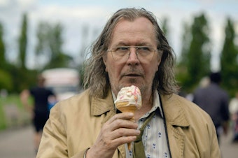 caption: In Apple TV+'s <em>Slow Horses</em>, Gary Oldman plays Jackson Lamb, the slovenly, brilliant spy who's in charge of a group of failed British spies. The series is based on Mick Herron's <em>Slough House</em> novels. Herron says Lamb might not have "a heart of gold" but he does have "a moral code."