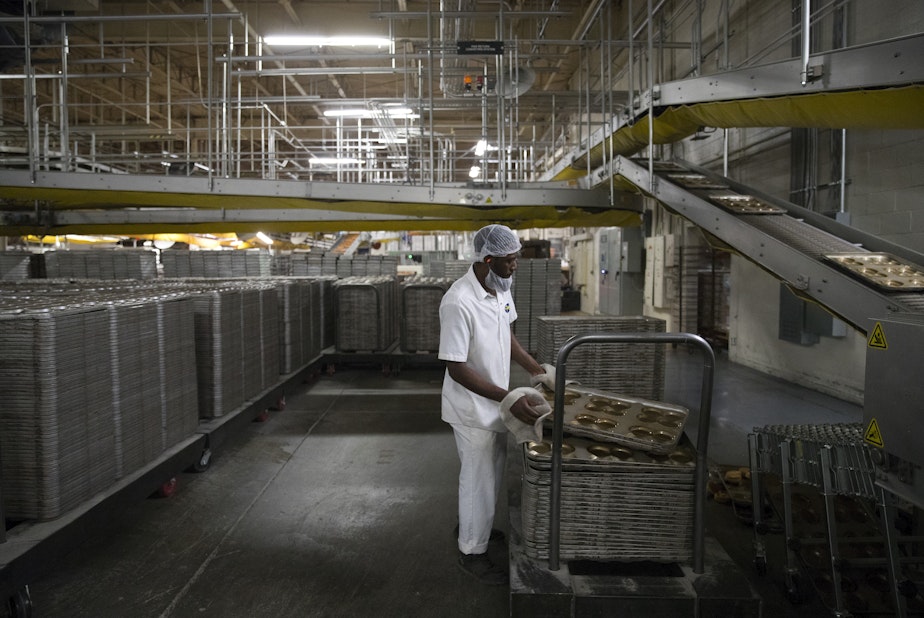 caption: Guy Patrice stacks trays at 10:05 p.m. on Wednesday, June 12, 2019, at Franz Bakery on 6th Avenue in Seattle. In one 8-hour night shift, between 48,000 and 50,000 loaves of bread are made. 