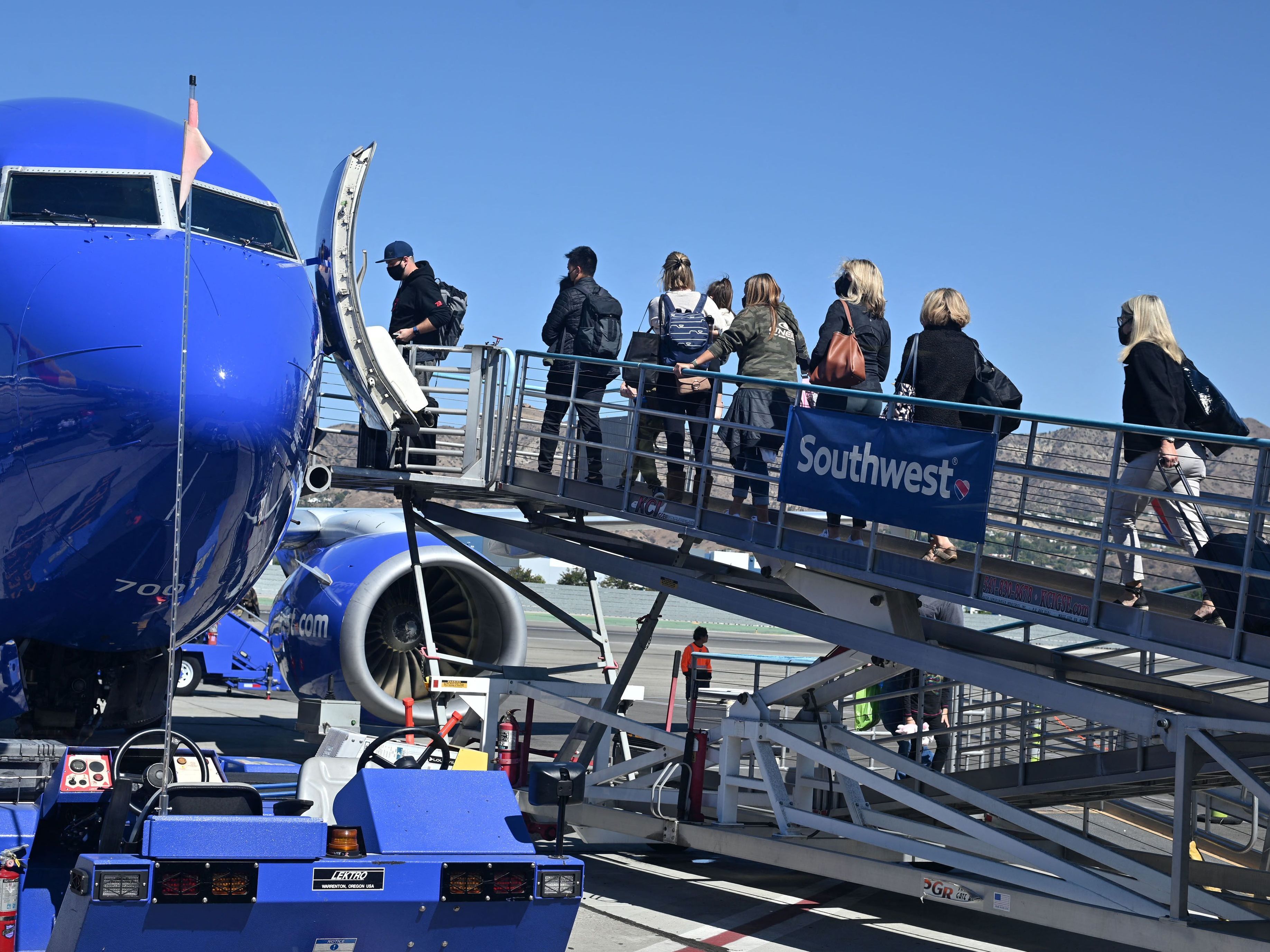 caption: Passengers board a Southwest Airlines airplane at Hollywood Burbank Airport in Burbank, California on October 10, 2021. The airline has continued to cancel or delay hundreds of flights on Monday.