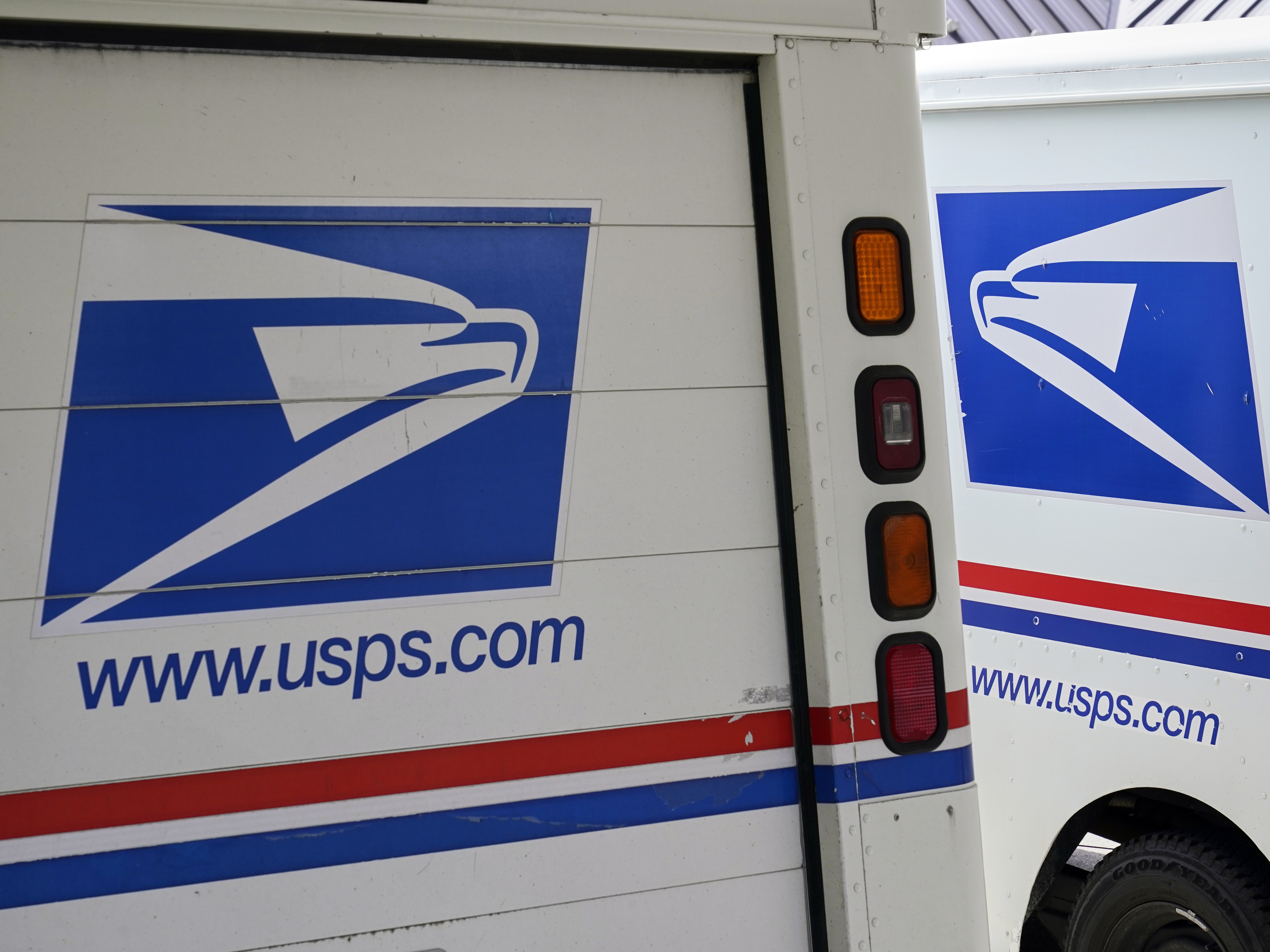 caption: U.S. Postal Service delivery vehicles are parked outside a post office in Boys Town, Neb., on Aug. 18, 2020.