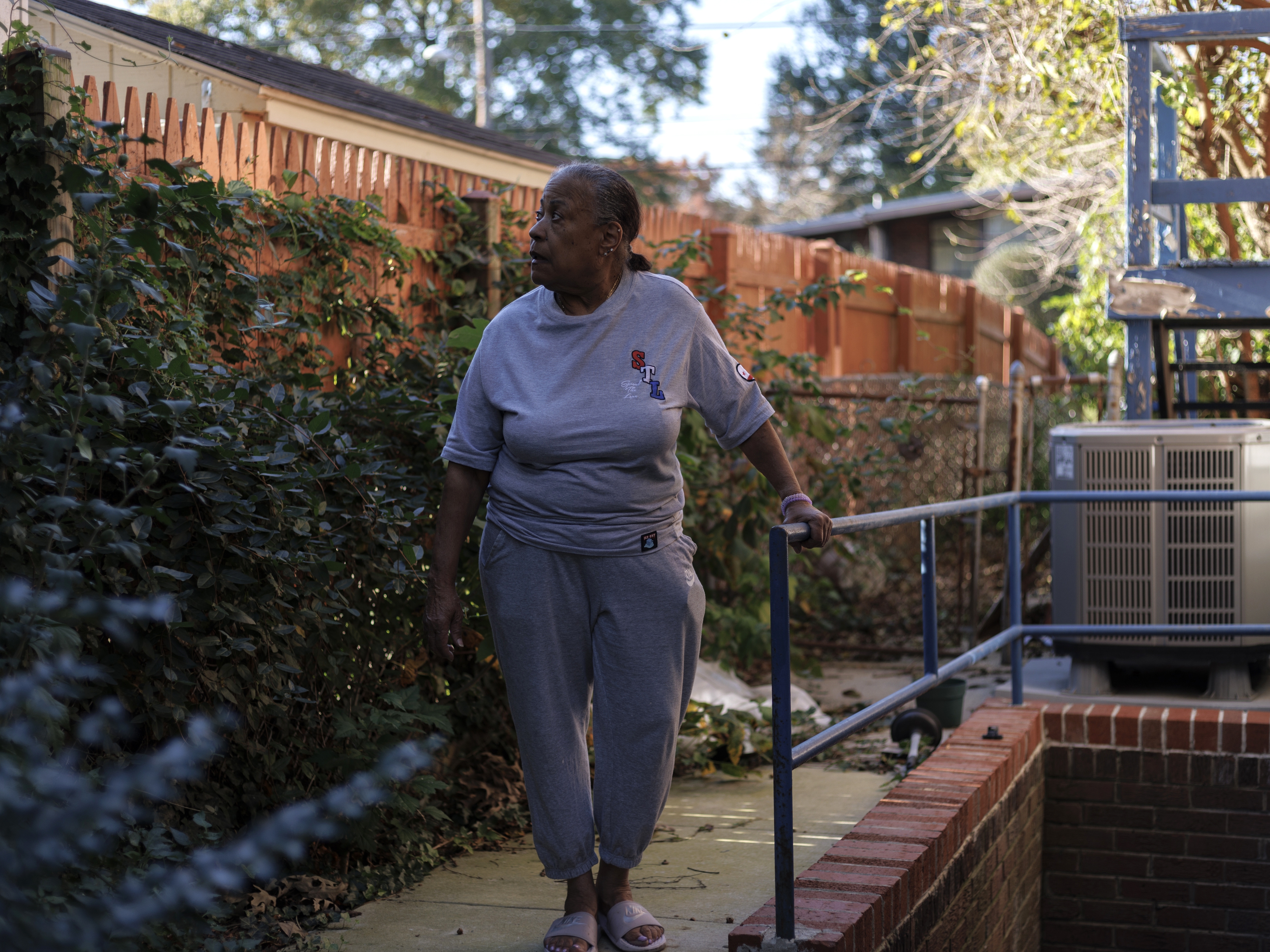 caption: Pat Haskins, a 72-year-old retired school teacher, poses for a portrait in the backyard of her home in Silver Spring, Md., on Oct. 22.  She had struggled to keep up with repairs as her basement flooded, a bathroom floor sagged and her disabled partner needed a ramp.