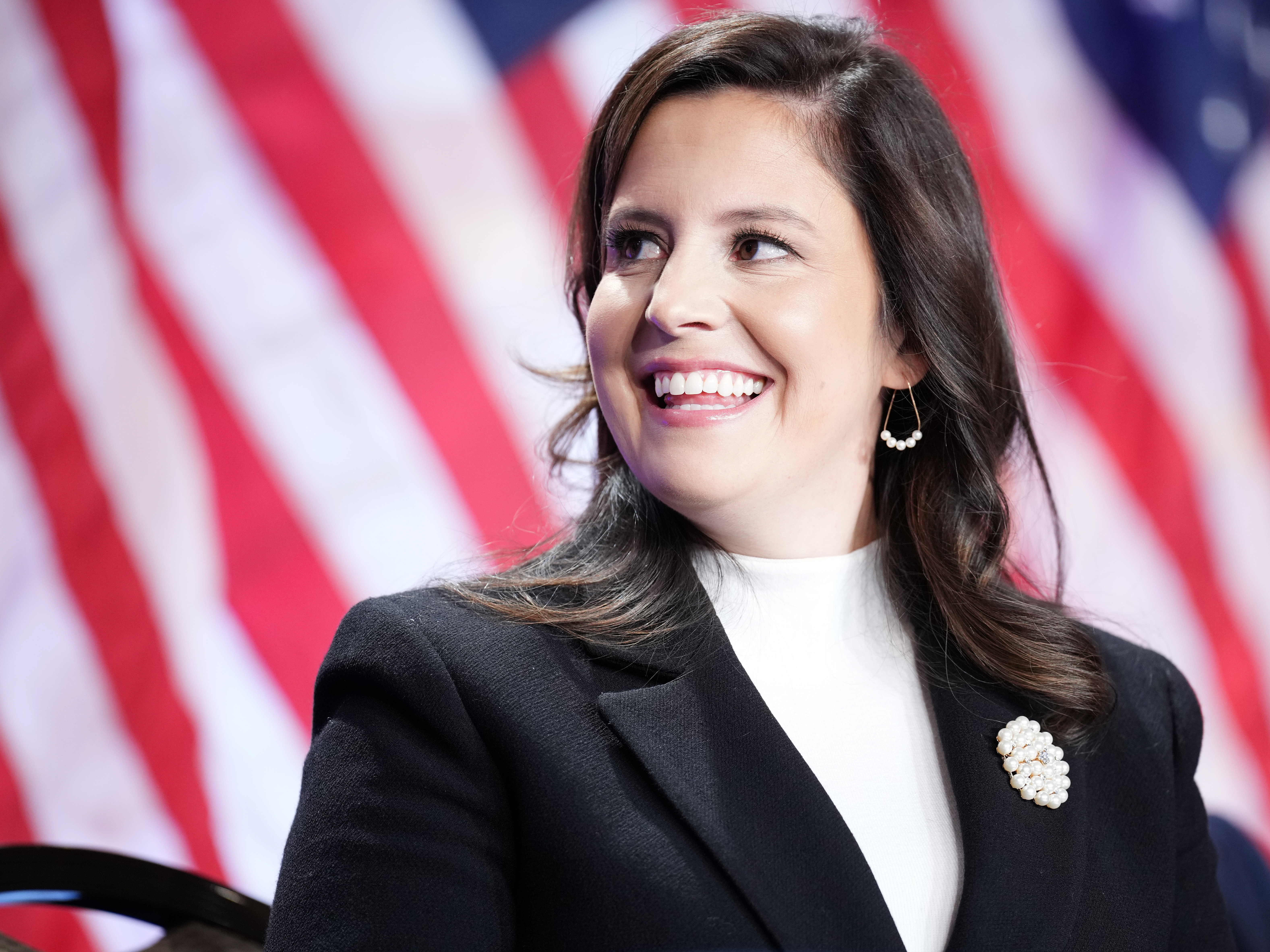 caption: House Republican Conference Chair Rep. Elise Stefanik (R-NY) listens as President-elect Donald Trump speaks at a meeting of the conference at the Hyatt Regency on Capitol Hill, in Washington, D.C., on Nov. 13, 2024.