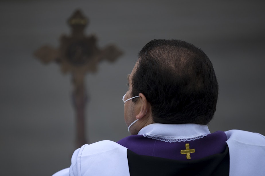 caption: Father Jose Alvarez waits for people to arrive for walk and drive through confessions on Friday, April 24, 2020, in the parking lot at Holy Family Roman Catholic Church in White Center. 