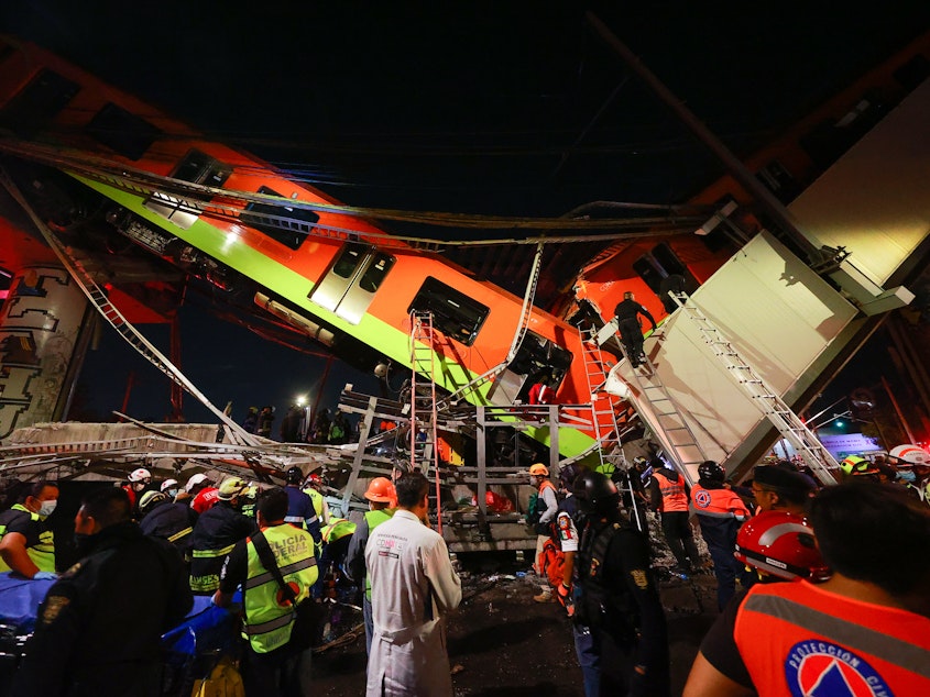 caption: Emergency personnel search for survivors after a raised subway track collapsed Monday night in Mexico City.