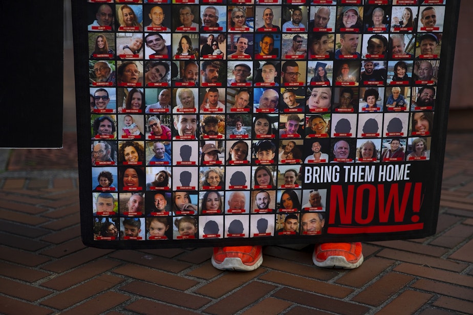 caption: Posters show images of hostages nearby to a multifaith solidarity gathering on Thursday, November 16, 2023, outside of the Henry M. Jackson Federal Building in Seattle. Four women have been standing daily between 11 a.m. and 1 p.m. with the signs.