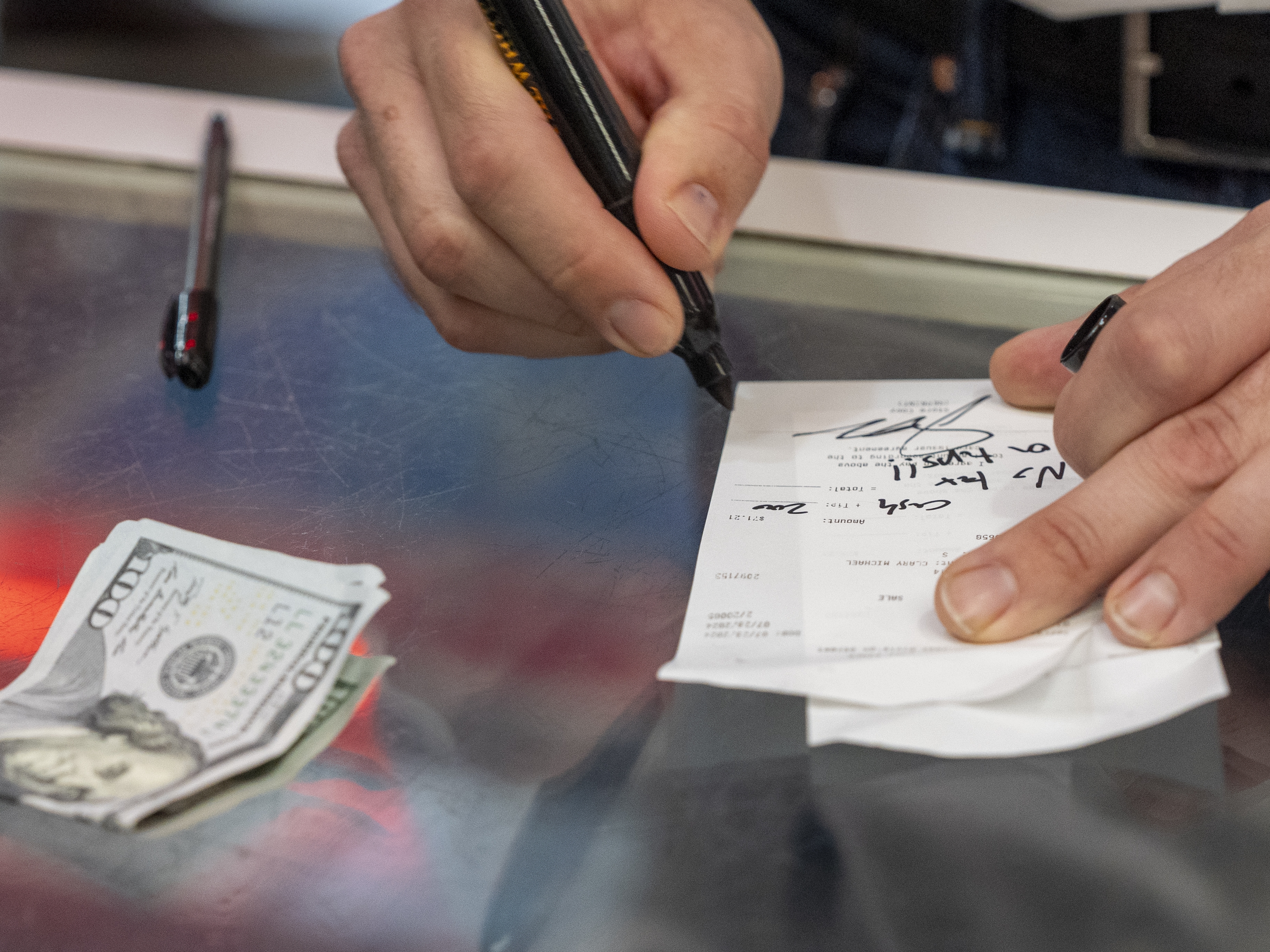 caption: Republican vice presidential candidate Sen. JD Vance, R-Ohio, signs a check "no tax on tips!!" as he leaves $200 in cash for a gratuity at the Park Diner, in Waite Park, Minn., on July 28.
