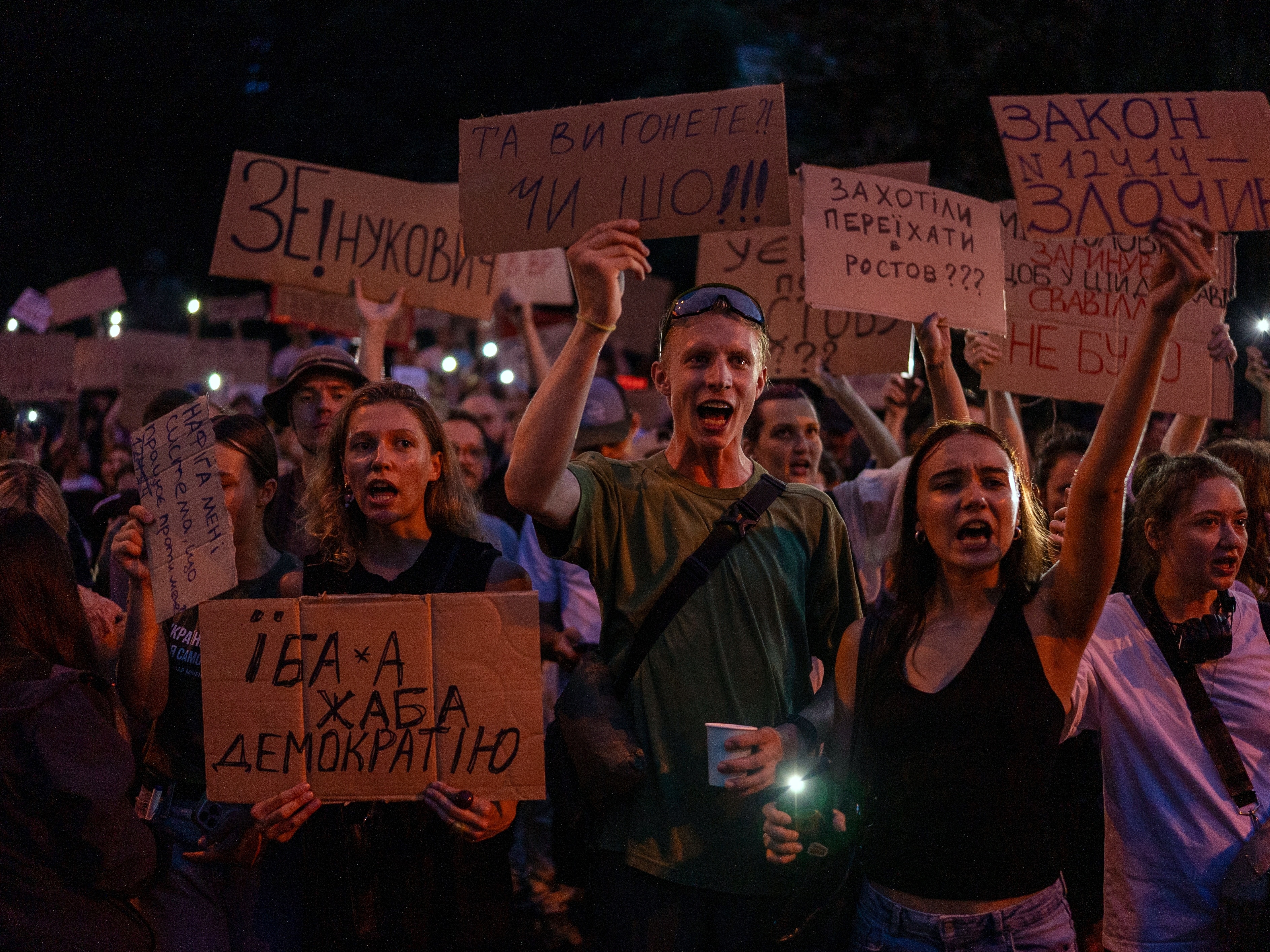 caption: People chant while holding banners during a protest against a law targeting anti-corruption institutions in central Kyiv, Ukraine, on Tuesday.