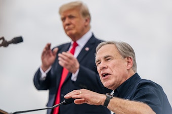 caption: Texas Gov. Greg Abbott speaks alongside former President Donald Trump during a tour of an unfinished section of the border wall on June 30 in Pharr, Texas. Abbott says he'll continue Trump's border barrier, a pledge that is expected to help the governor in his reelection campaign.