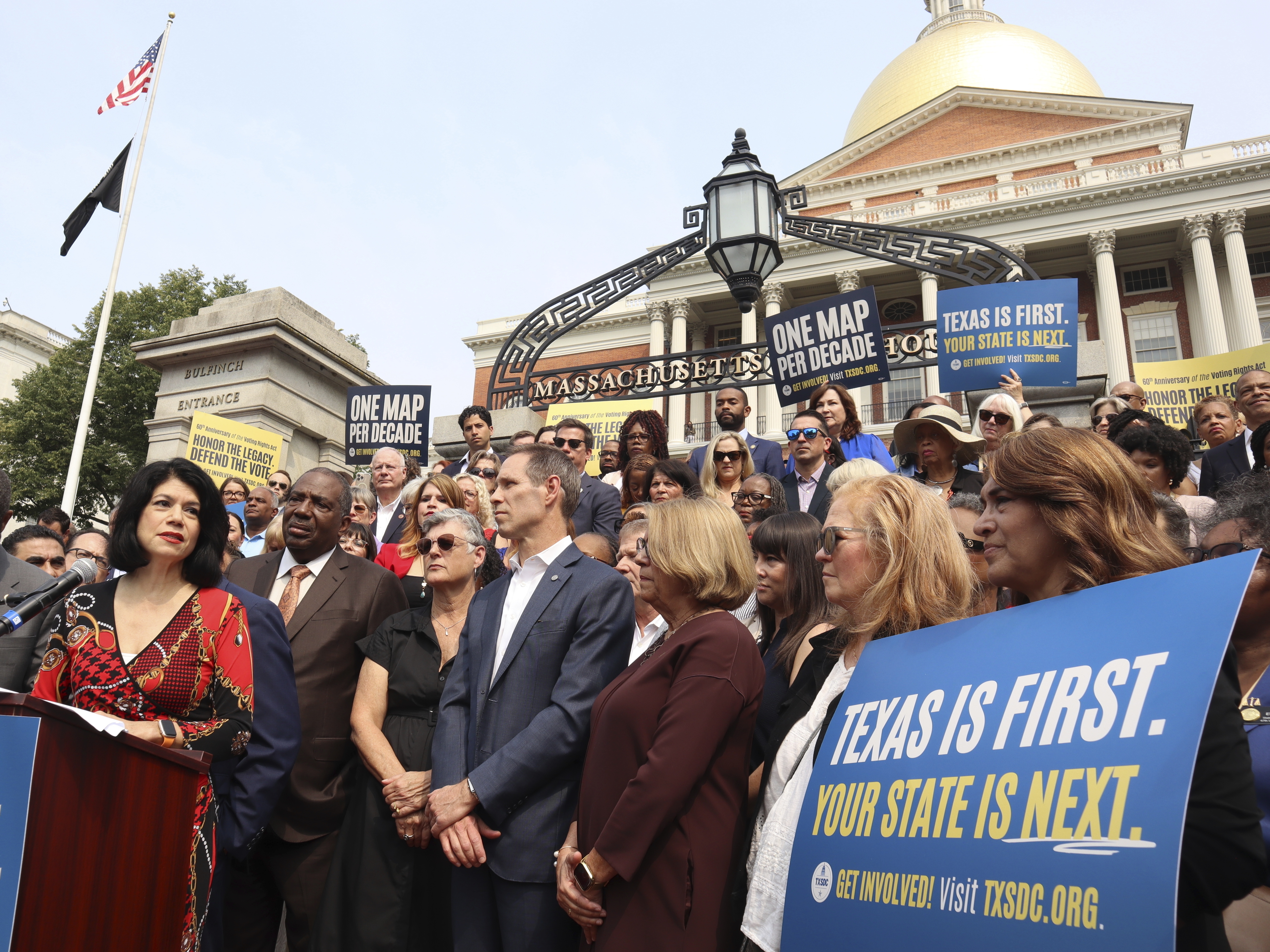 caption: Texas state Senator Carol Alvarado, a Democrat, speaks in a crowd of other Democratic state lawmakers outside the Massachusetts State House on Wednesday, Aug. 6, 2025 in Boston.