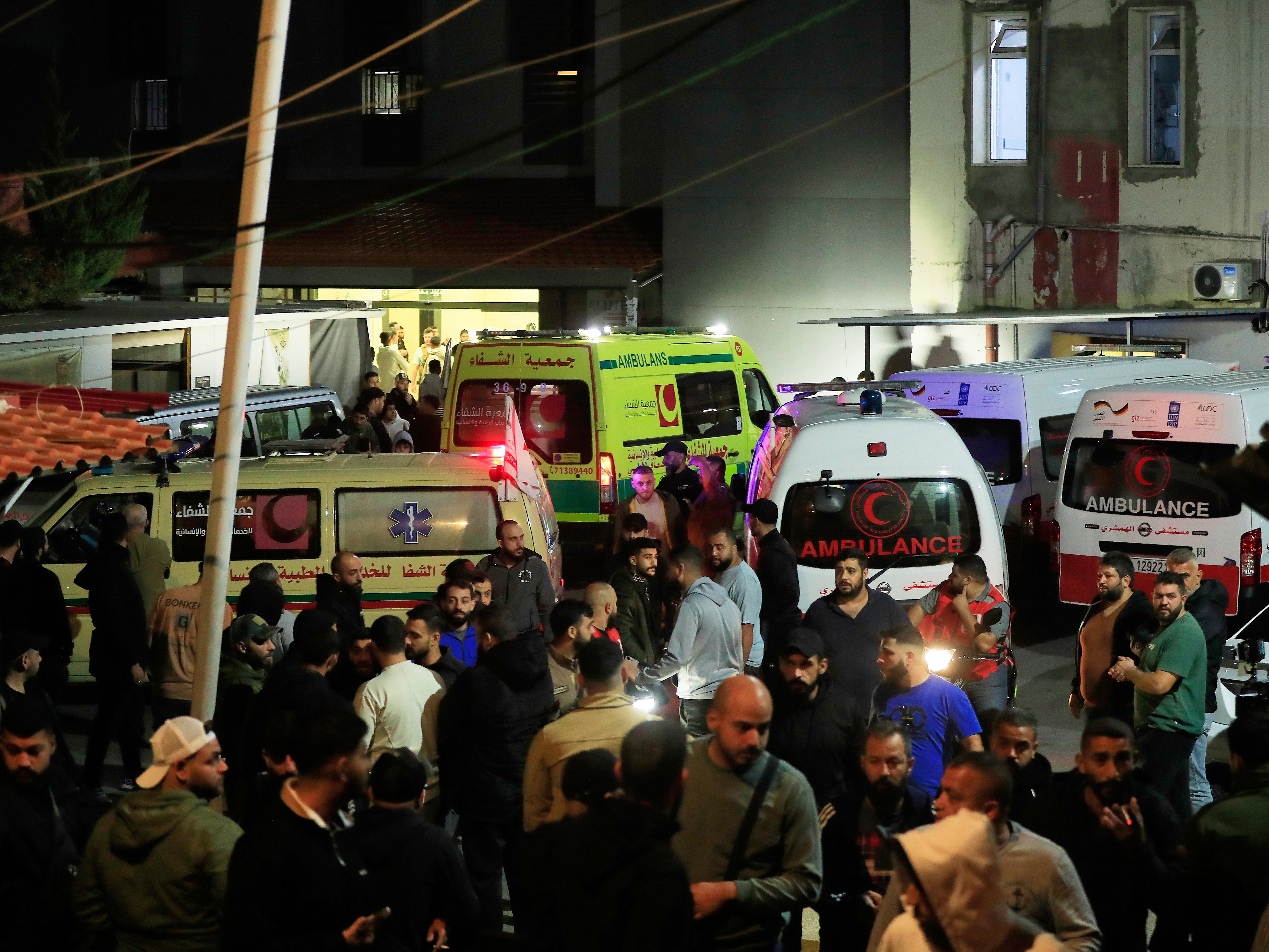 caption: People gathering next of ambulances outside a hospital where they brought the victims of the Israeli strike that hit the Ein el-Hilweh refugee camp in the southern port city of Sidon, Lebanon, on Tuesday.