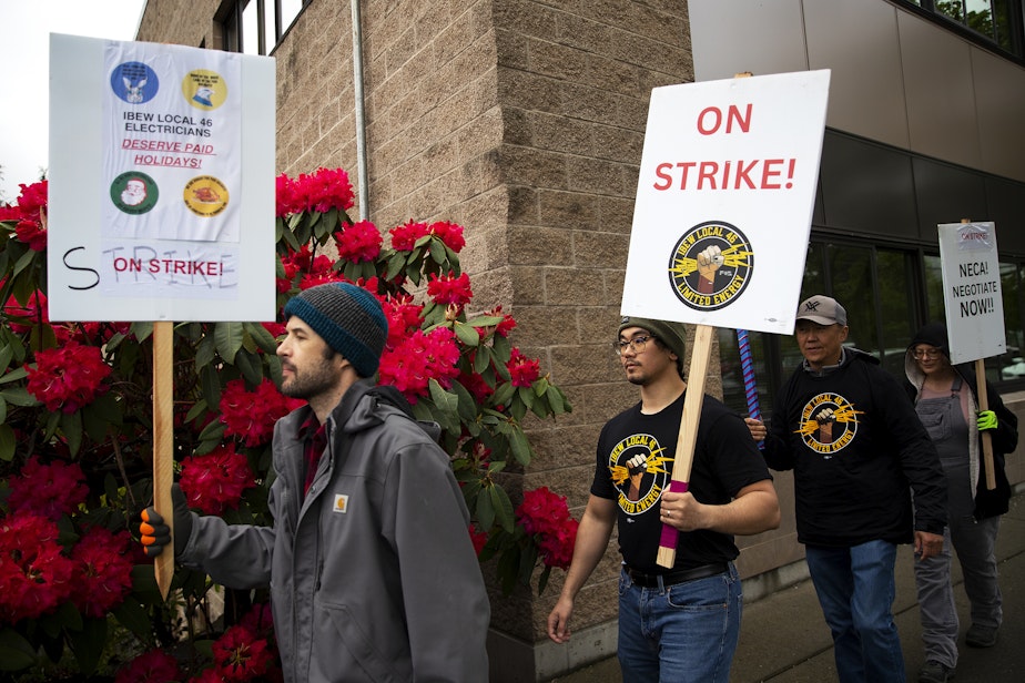 caption: IBEW Local 46 workers, including Ian Cochran-Keith, left, and John Carandang, second from left, picket while on strike on Friday, April 26, 2024, along Stone Avenue North in Seattle. 