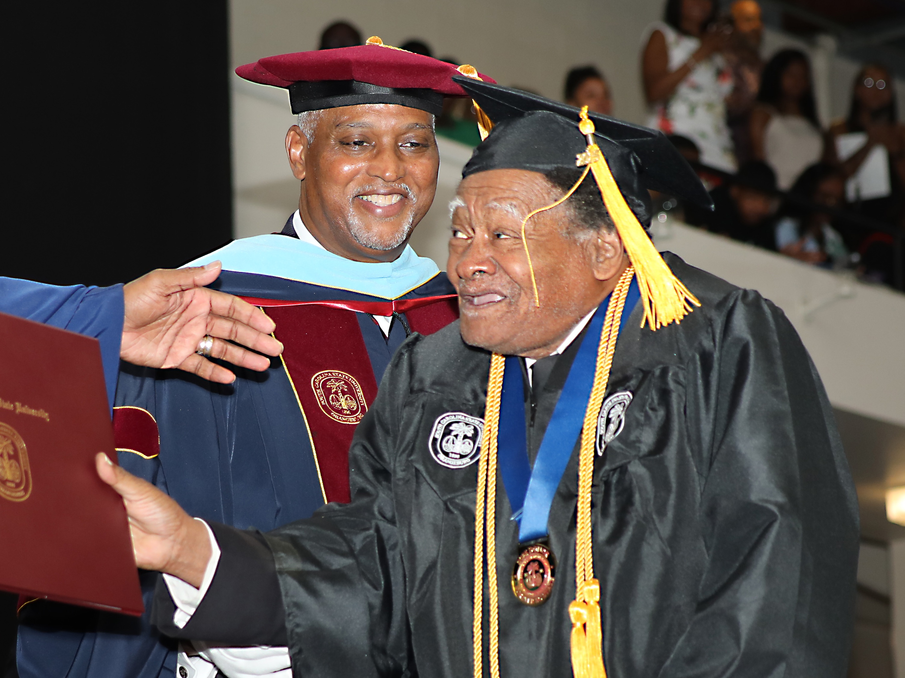 caption: Linwood Riddick, who turns 80 on Monday, accepts his bachelor's degree at South Carolina State University on Friday May 9th.