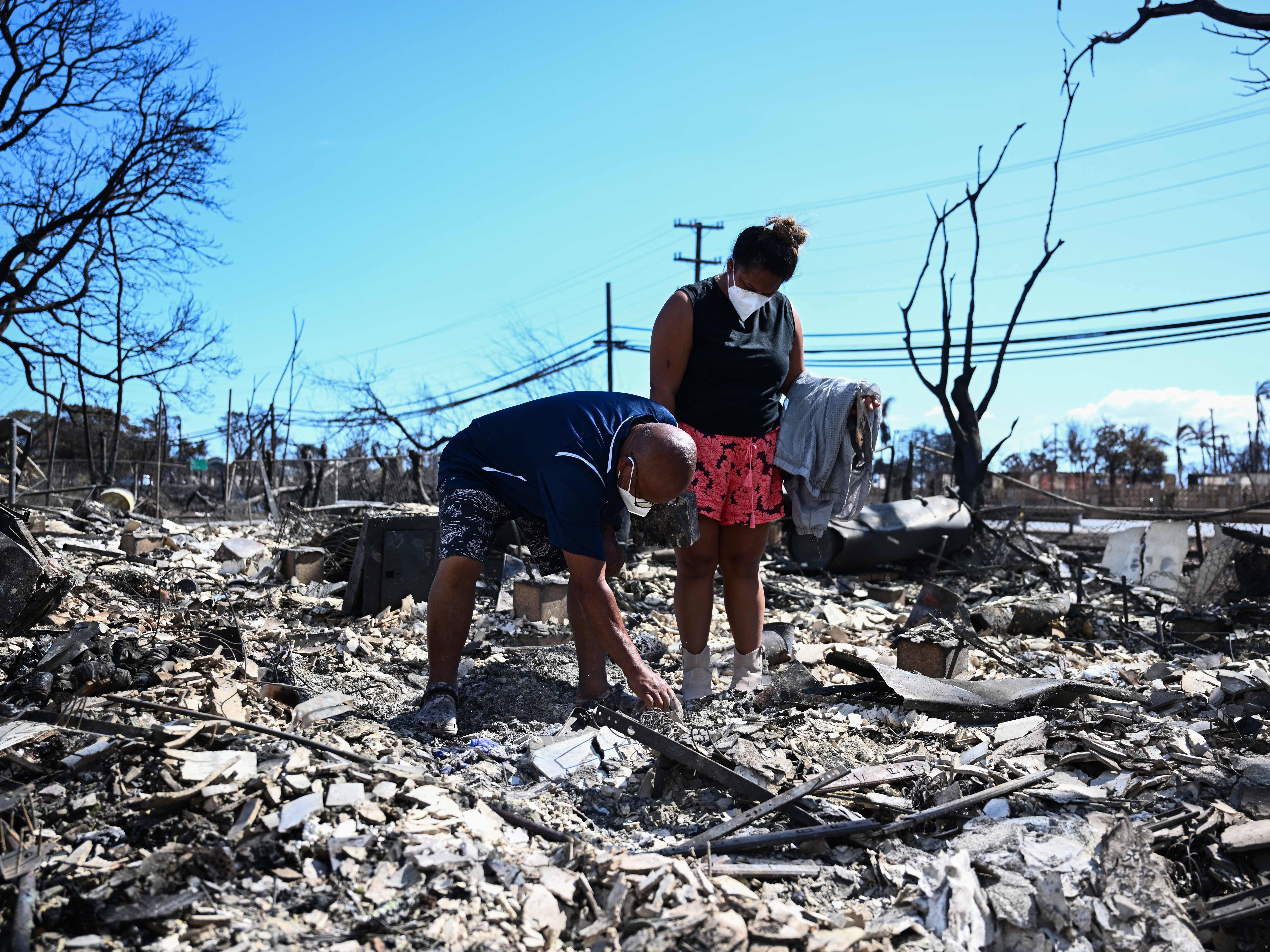 caption: Davilynn Severson and Hano Ganer look for belongings through the ashes of their family's home on Friday in the aftermath of a wildfire in Lahaina, in western Maui, Hawaii.
