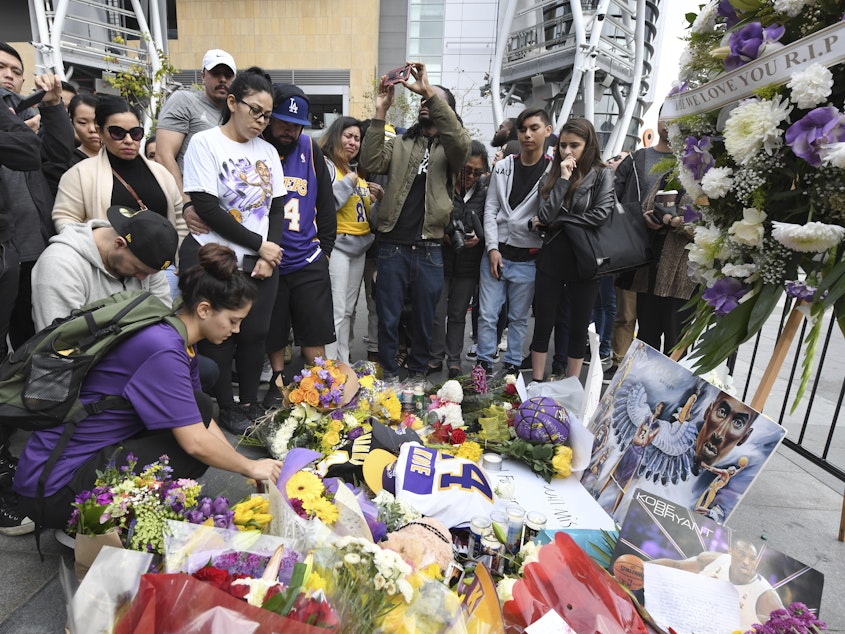 caption: Valerie Samano, left, places flowers at a memorial near the Staples Center in Los Angeles, after the death of Laker legend Kobe Bryant on Sunday.