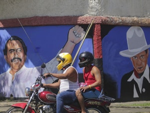caption: A motorcyclist rides past a mural of Nicaraguan President Daniel Ortega, left, and revolutionary hero CÃ©sar Augusto Sandino<em> </em>during general elections in Managua, Nov. 7, 2021. Ortega won a fourth consecutive term against a field of little-known candidates while those who could have given him a real challenge sat in jail.
