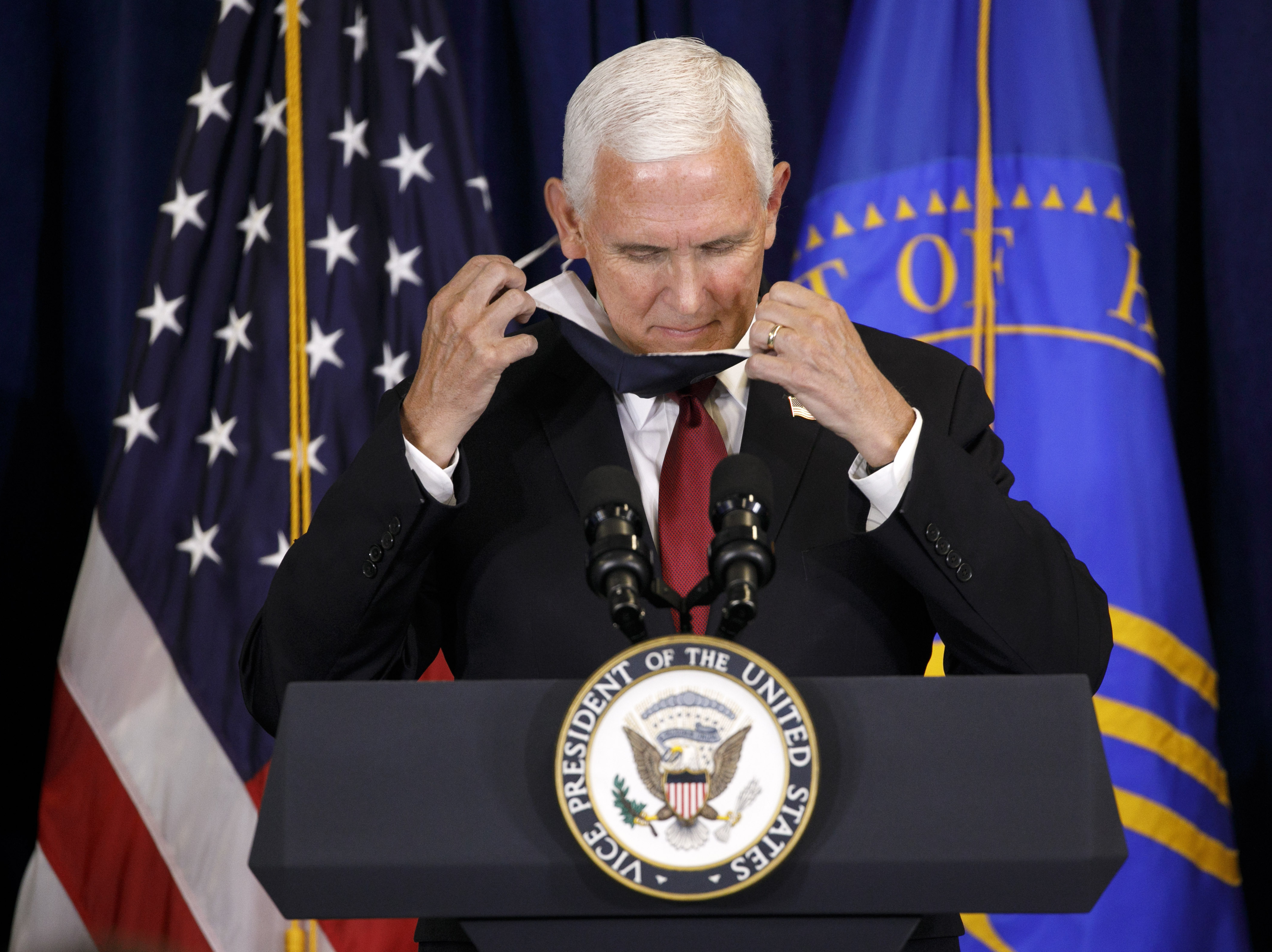 caption: Vice President Pence removes his mask as he arrives at the lectern to speak to the U.S. Public Health Service at its headquarters in Rockville, Md., on Tuesday.