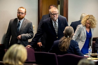 caption: Greg McMichael (center) and his son Travis McMichael (left) look at family members seated in the gallery when they walk into the courtroom for the reading of the jury's verdict for themselves and a neighbor, William "Roddie" Bryan, in the Glynn County Courthouse on Nov. 24, 2021, in Brunswick, Ga. The three men were charged with the fatal shooting of 25-year-old Ahmaud Arbery in 2020.