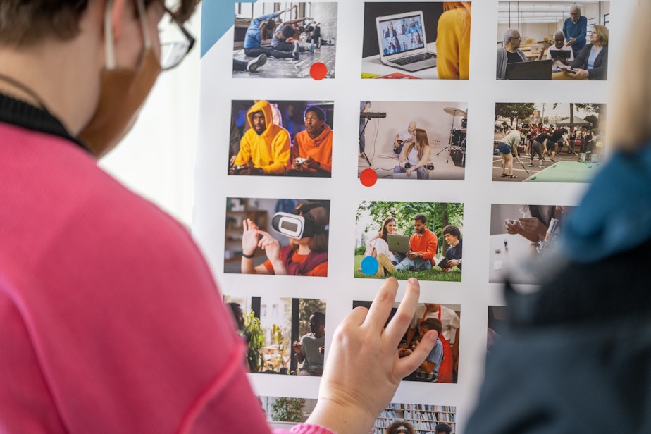 caption: A sign shows pictures of people playing games, trying virtual reality headsets, groups doing yoga or having online meetings. These pictures depict all of the programs and services a library could offer.