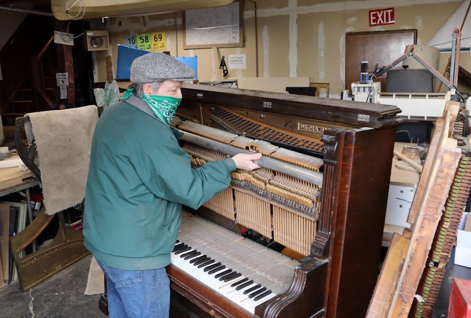 caption: Michael Rohde disassembling a 120-year-old piano to salvage the metal and fine wood for other uses.
