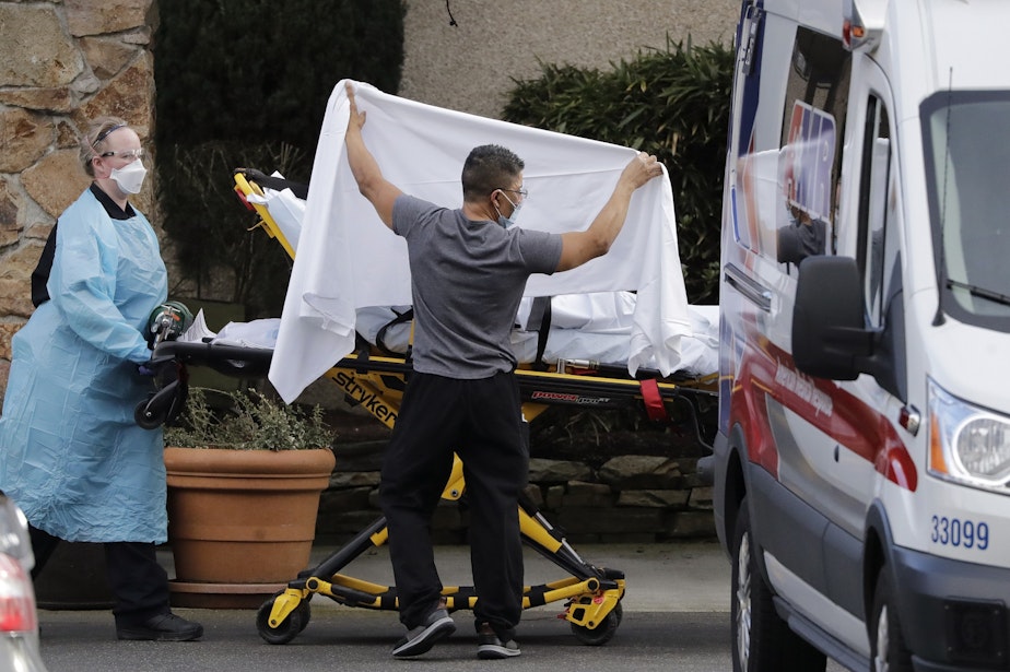 caption: A staff member blocks the view as a person is taken by a stretcher to a waiting ambulance from a nursing facility where more than 50 people are sick and being tested for the COVID-19 virus, Saturday, Feb. 29, 2020, in Kirkland, Wash. 
