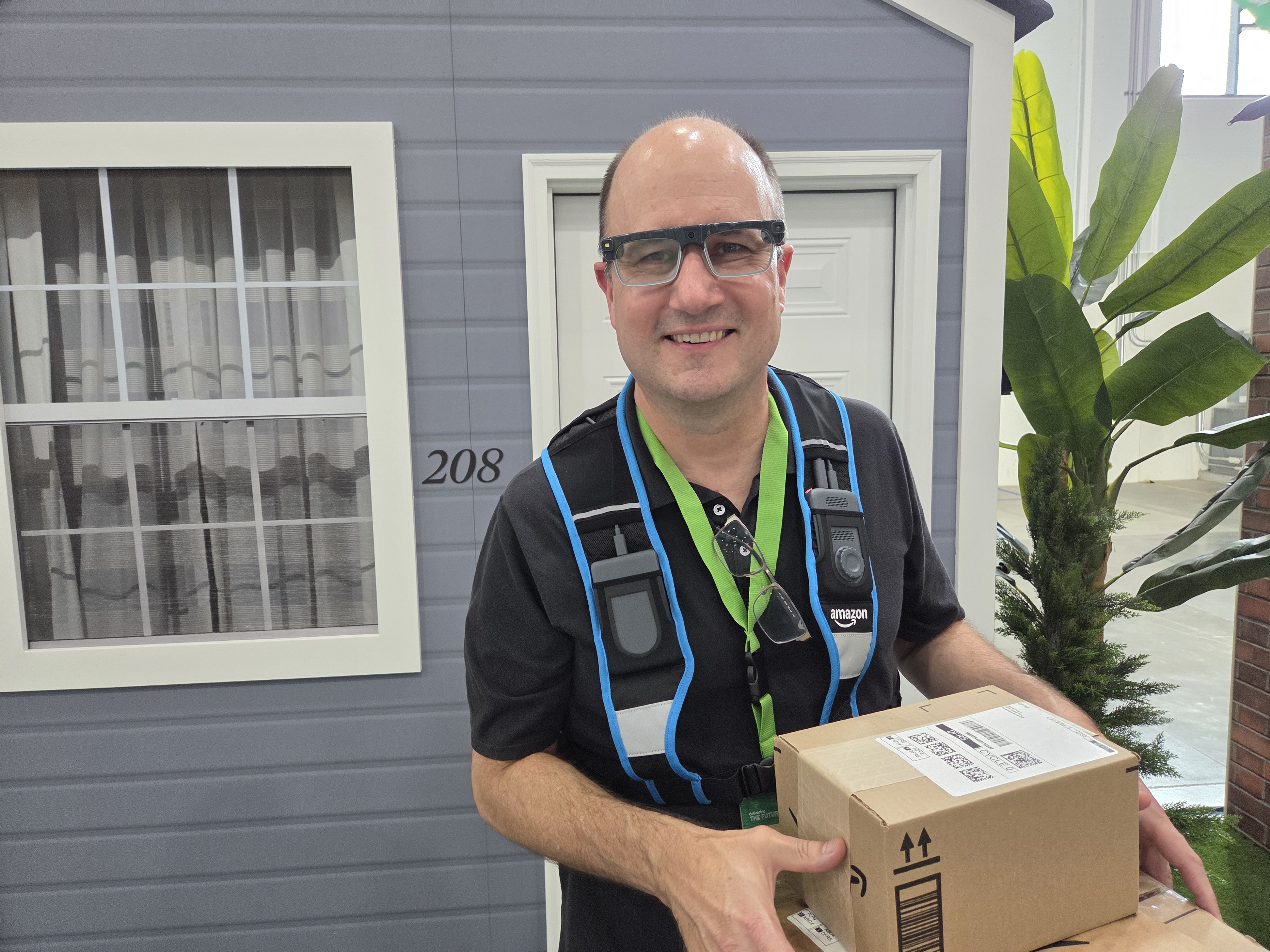 caption: GeekWire's Todd Bishop delivering packages in Amazon's new smart glasses.