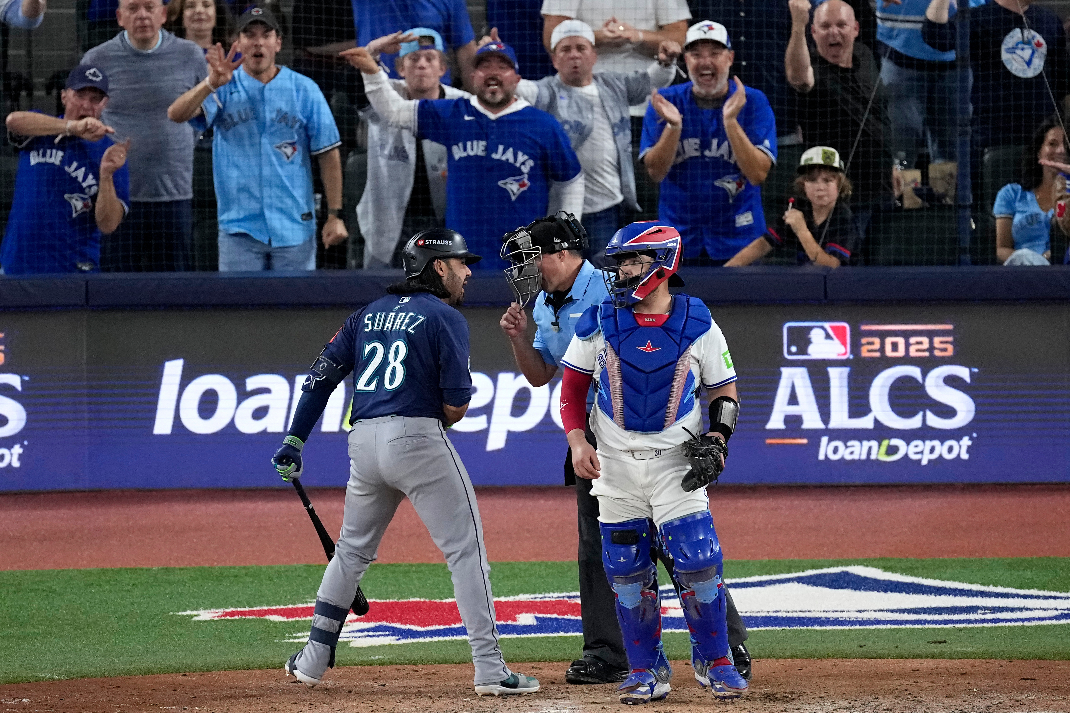 caption: Seattle Mariners' Eugenio Suárez argues a called strike three with home plate umpire Quinn Wolcott during the eighth inning in Game 7 of baseball's American League Championship Series against the Toronto Blue Jays, Monday, Oct. 20, 2025, in Toronto. 