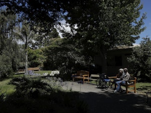 caption: Larry Yarbroff visits his wife Mary at Chaparral House in Berkeley, Calif. in July. California health authorities had allowed some visits to resume, and now federal regulators are doing the same, with measures to try to block the spread of the coronavirus.