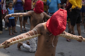caption: Hooded Filipino penitents carry pointed bamboo sticks as part of Maundy Thursday rituals to atone for sins or fulfill vows for an answered prayer on April 6, 2023 at Mandaluyong city, Philippines.
