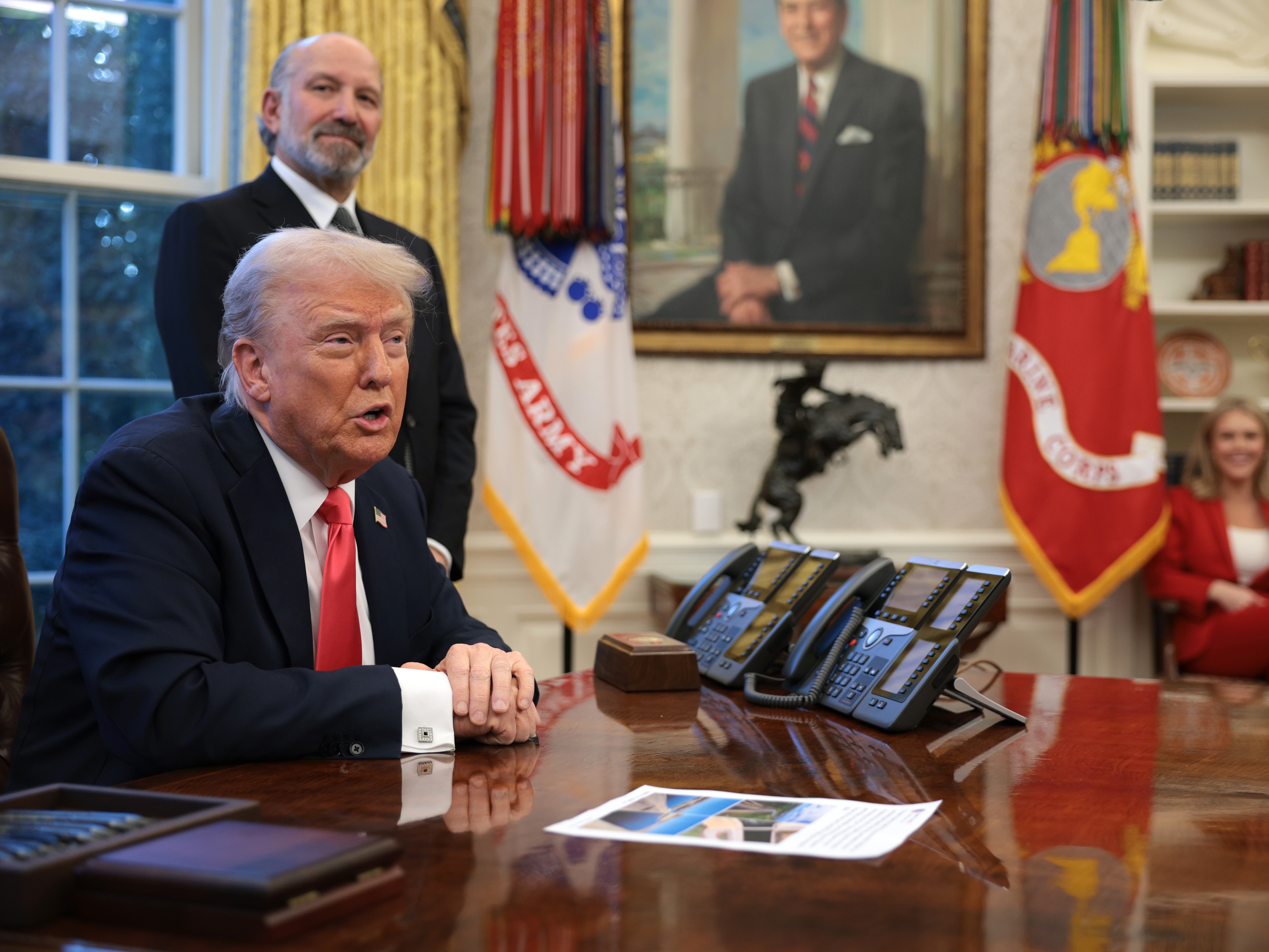 caption: President Trump speaks to reporters as Commerce Secretary Howard Lutnick looks on in the Oval Office on Feb. 25, 2025.