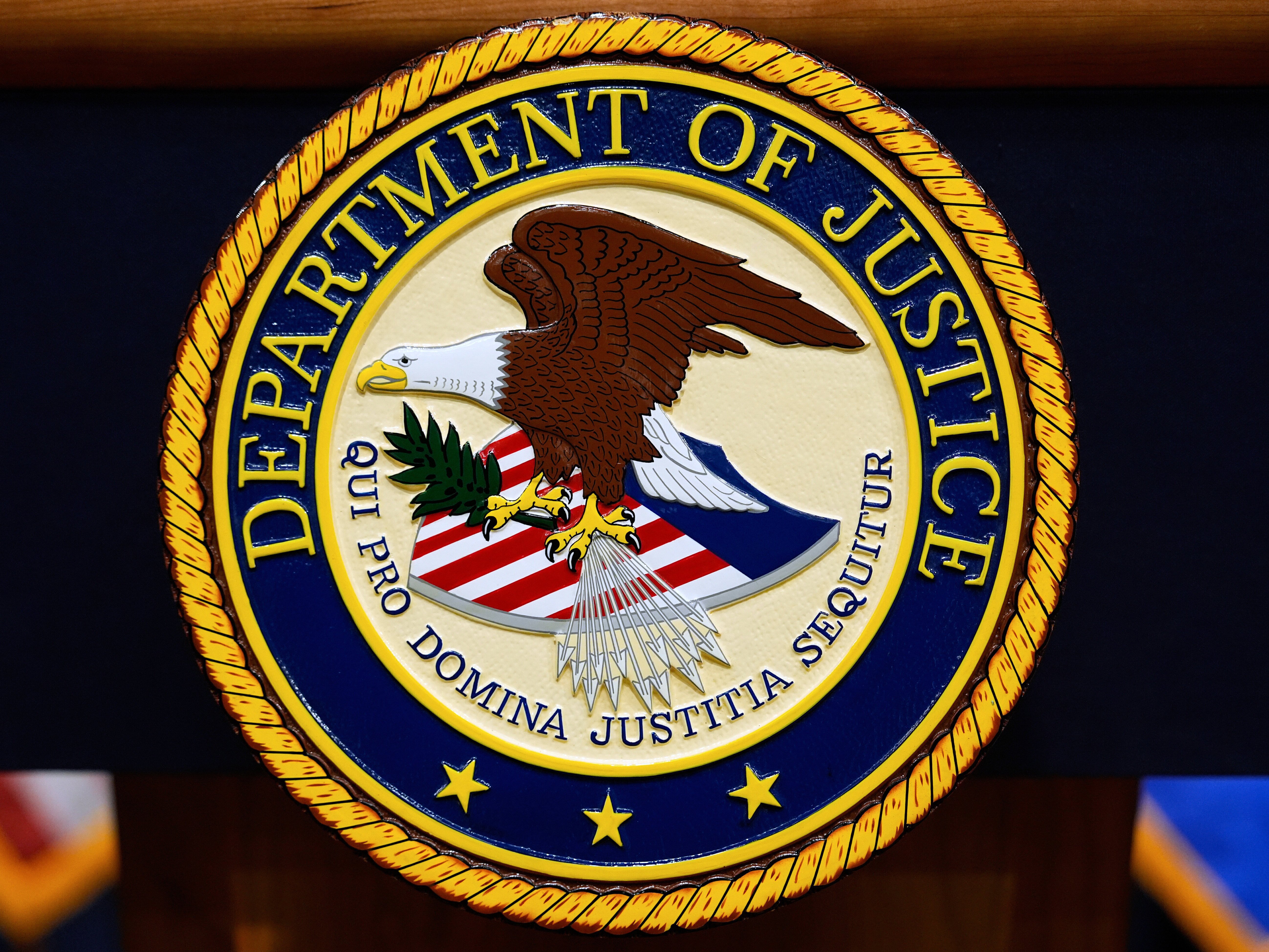 caption: The U.S. Department of Justice logo is seen on a podium before a news conference at the Justice Department in Washington, on May 6, 2025.