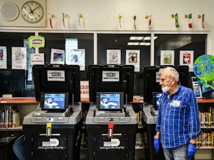 caption: An election worker at a poling station in Miami during last month's election there. The coronavirus pandemic is challenging election officials, whose own staffers are coming sick with the virus.