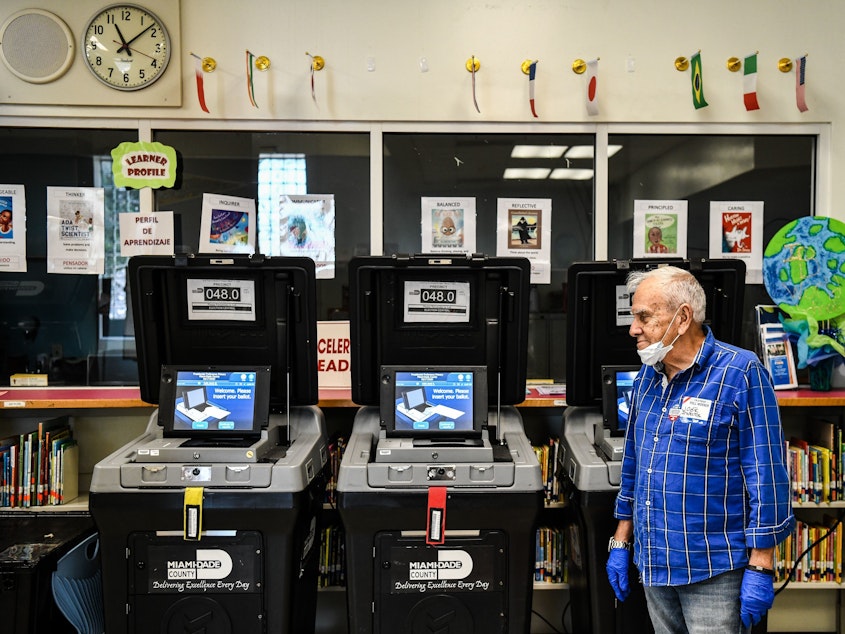 caption: An election worker at a poling station in Miami during last month's election there. The coronavirus pandemic is challenging election officials, whose own staffers are coming sick with the virus.