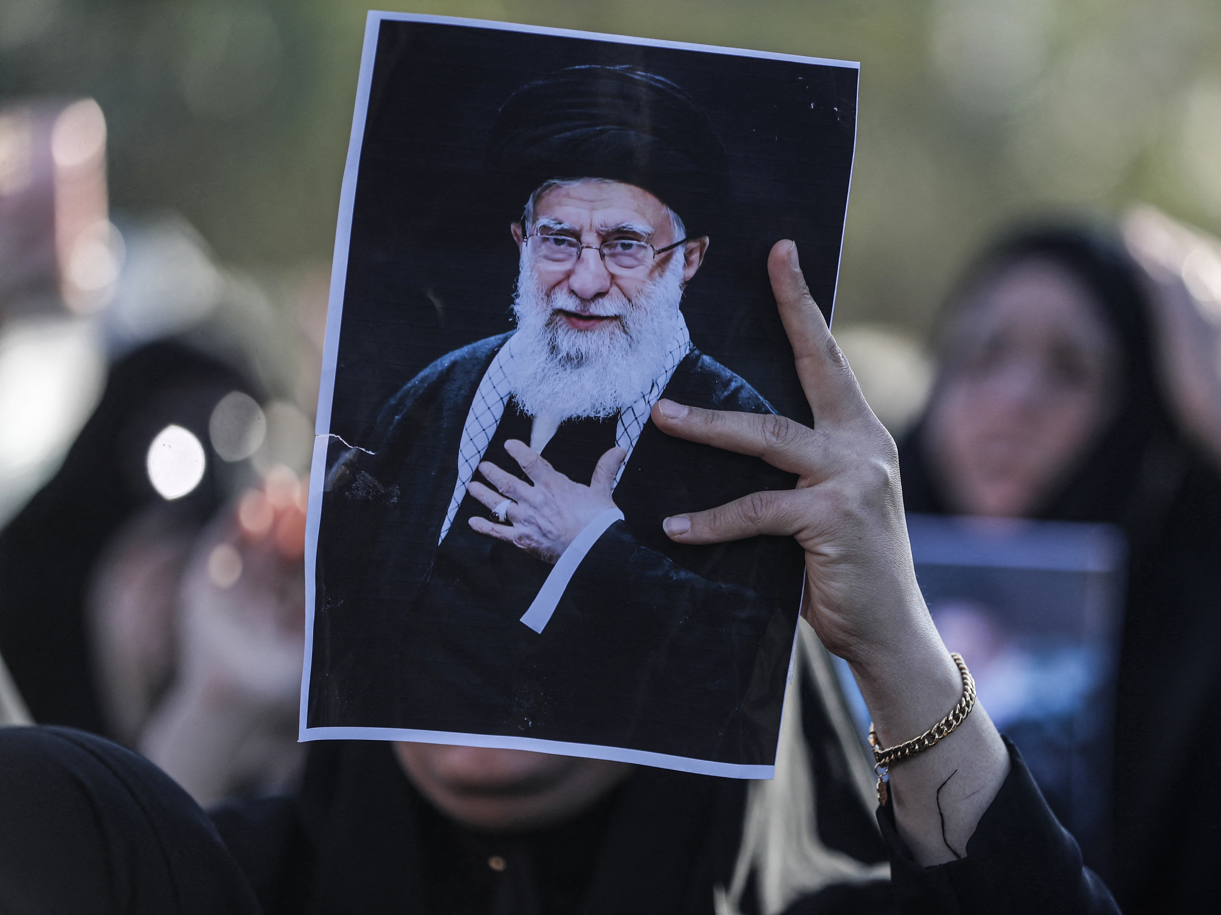 caption: An Iraqi Shiite Muslim woman holds up the image of killed Iranian supreme leader Ayatollah Ali Khamenei, during a symbolic funeral the day after his assassination, in the district of Sadr City, in Baghdad on March 1, 2026.