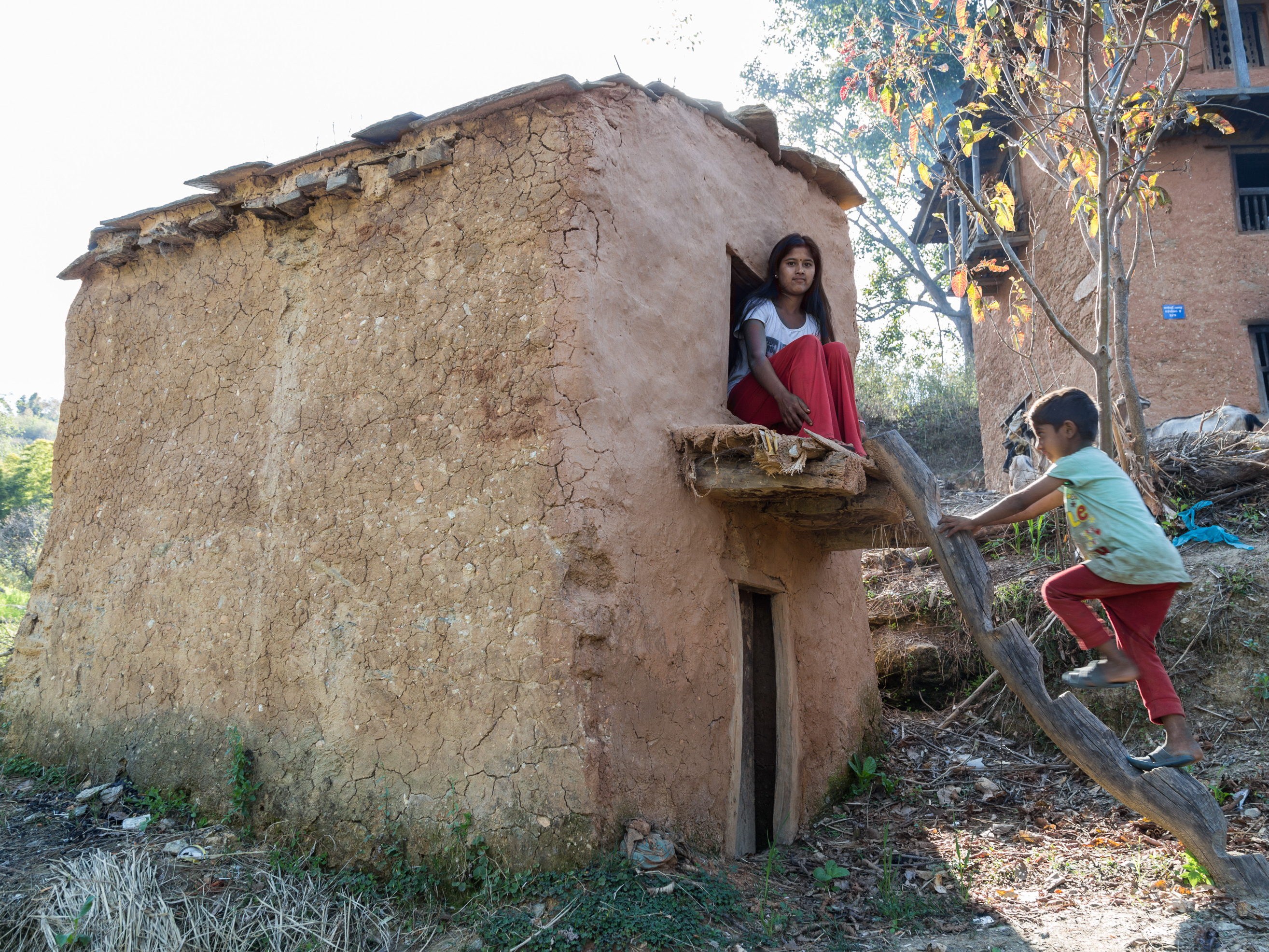caption: Manisha Jaisi, 16, poses at the shed outside her house where she sleeps when she has her period. Jaisi got her period two months after her neighbor, Dambara Upadhyay, died while sleeping in a similar shed in 2016 of unknown causes. Jaisi says she never goes without her phone in the shed because she's scared after Upadhyay's death.