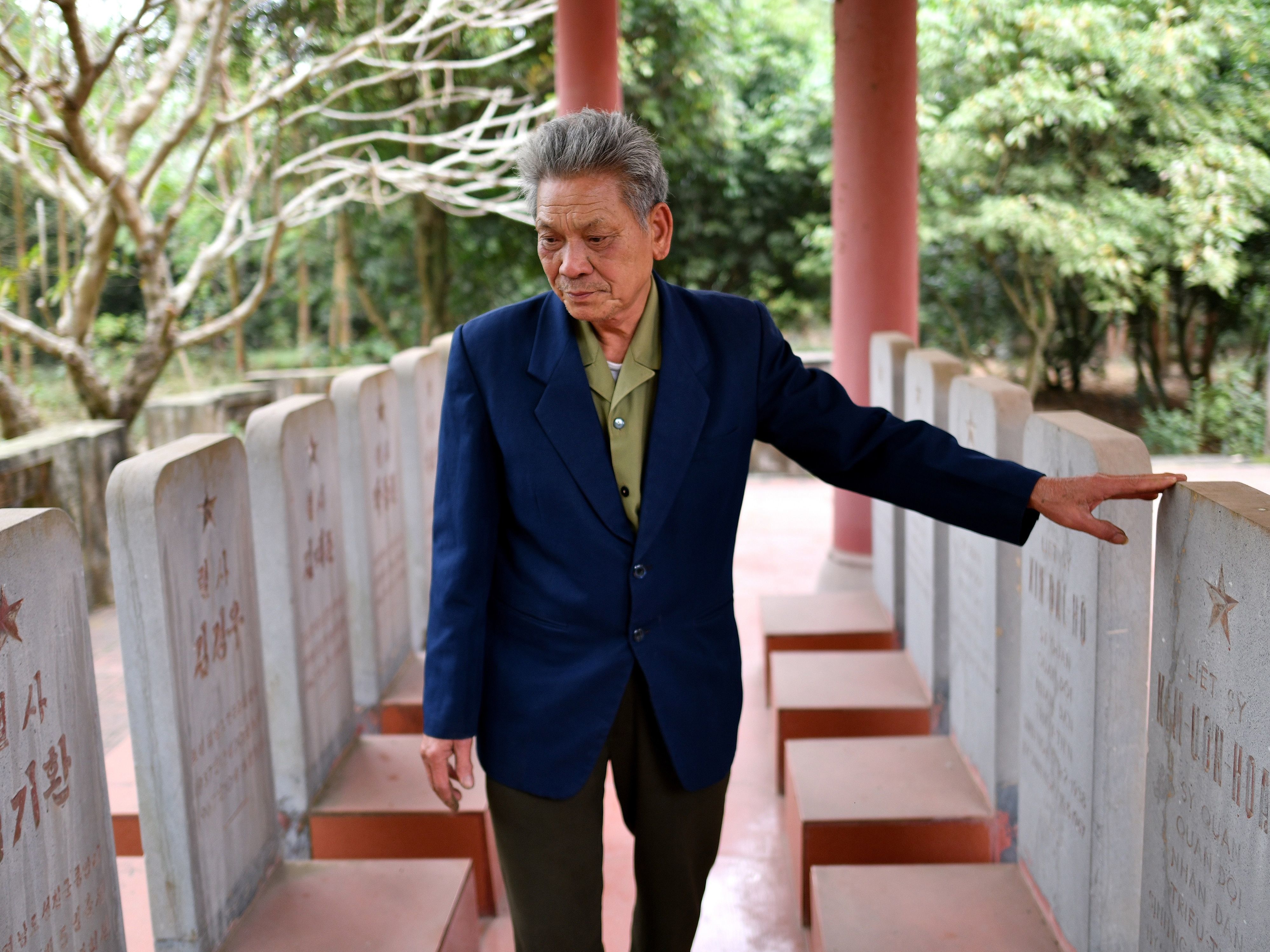 caption: At a war memorial in Bac Giang province, Duong Van Dau views the tombstones of North Korean pilots killed during the Vietnam War. Headstones are etched with the names of the dead in Korean on one side, and Vietnamese on the other.