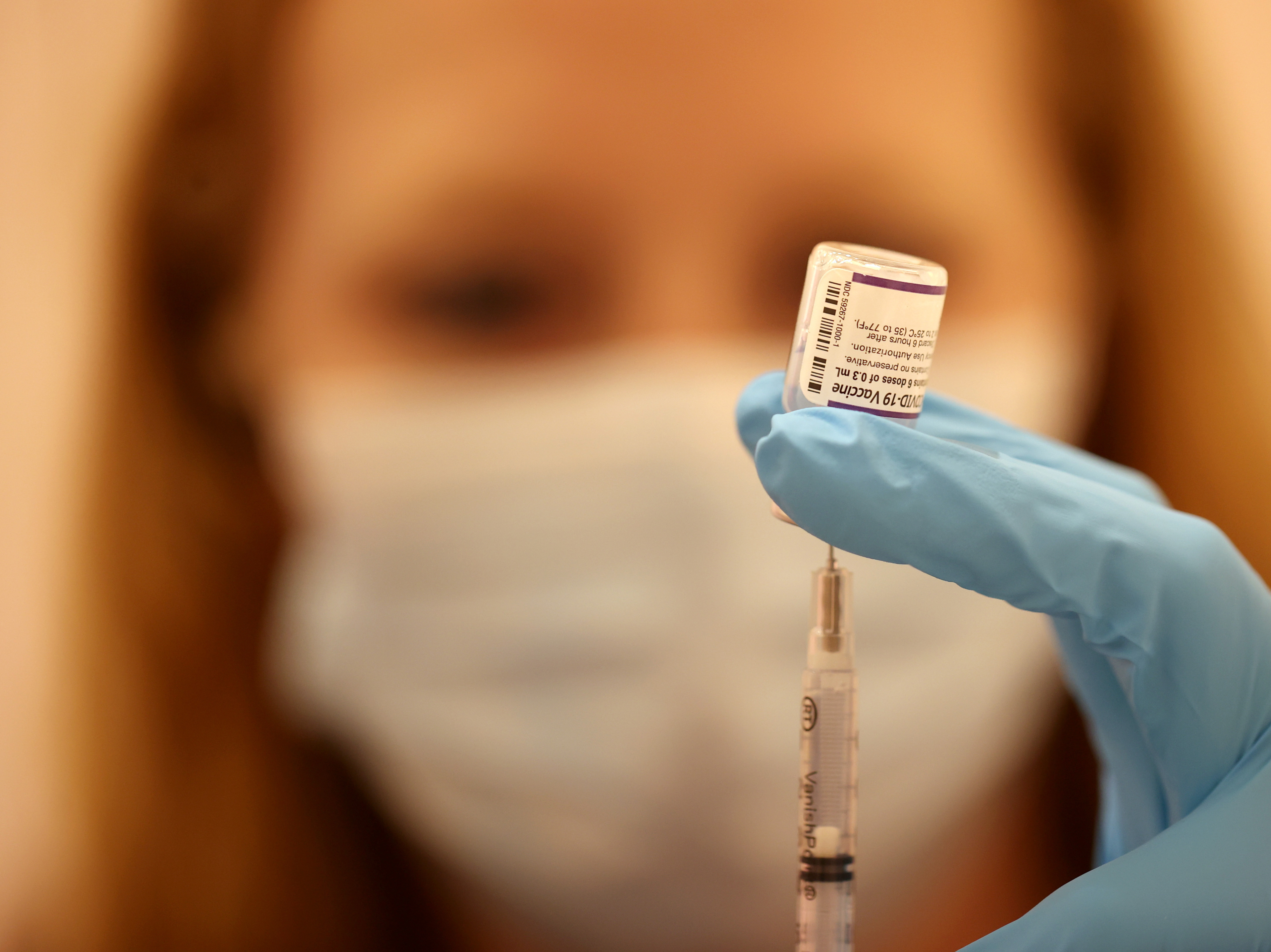 caption: Safeway pharmacist Ashley McGee fills a syringe with the Pfizer COVID-19 booster vaccination at a vaccination booster shot clinic on Oct. 1, in San Rafael, Calif.
