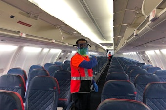 caption: Lemlem Awraris of ERMC Aviation services prepares to fog a Delta Air Lines plane with disinfectant on Wednesday, June 17, 2020. 