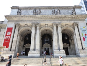 caption: People walk along the stairs of the New York Public Library on July 06, 2021 in Midtown Manhattan in New York City.