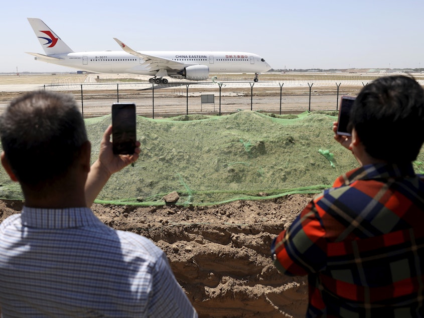caption: FILE - Residents watch as a China Eastern passenger jet prepares to take off on a test flight from the new Beijing Daxing International Airport on Monday, May 13, 2019. State media are reporting a Chinese airliner from China Eastern with 133 people on board crashed in the southern province of Guangxi on Monday.