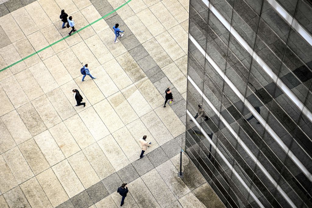 caption: People walk by an office building at the business district of La Defense west of Paris on October 7, 2020. (Christophe ARCHAMBAULT / AFP)  
